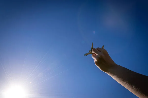 Speelgoed kinderen vliegtuig in zonlicht blauwe hemel. Wit vliegtuig in de hand vliegen in felle zon licht lucht achtergrond. Vliegtuigconcept. — Stockfoto