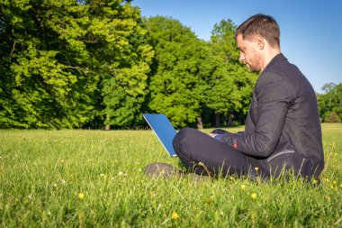 Dışarıda dizüstü bilgisayarla çalış. Bilgisayarlı öğrenci, yazlık doğa parkında tablet. Çocuk dışarıda internet teknolojisiyle iş yapıyor. Elektronik aletler uzaklık öğrenme konsepti.