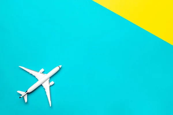 Plane banner. White toy airplane on bright blue and yellow background. Flight in sky, aircraft fly in air travel concept.