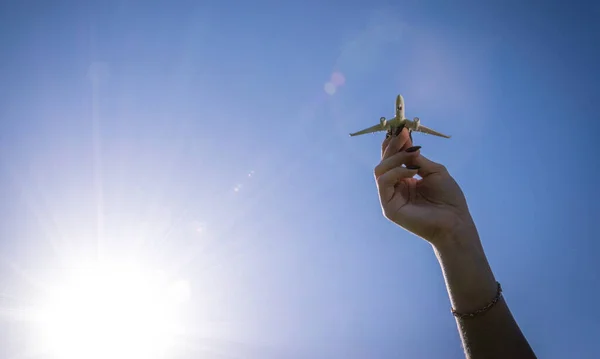 太陽の光の日におもちゃを遊んでいる子供たち 手の中の白い飛行機は青い日差しの空を飛ぶ 飛行機 航空機の飛行明るい背景にあります 旅行のコンセプト — ストック写真