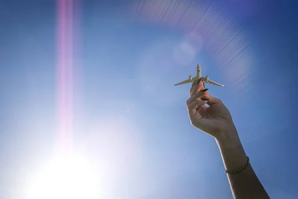 太陽の光の空に飛行機の翼 女の子の手で白い飛行機のおもちゃの明るい日差しの背景に飛ぶ 航空機の旅のコンセプト — ストック写真