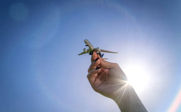 太陽の光の中でおもちゃの子供飛行機青空 手の中に白い旅行飛行機の明るい太陽の光の空気の背景に飛ぶ 航空機飛行の概念 — ストック写真