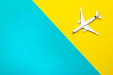 Seyahat geçmişi. Beyaz oyuncak uçak, parlak mavi ve sarı zemin üzerinde uçak. Gökyüzü uçak konseptinde uç ya da uç
