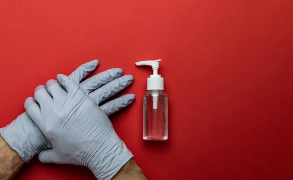 Medical background red. Medical antibacterial sanitizer gel and lab gloves on Virus protection equipment background. Clear sanitizer in pump bottle. Novel Coronavirus 2019-nCoV