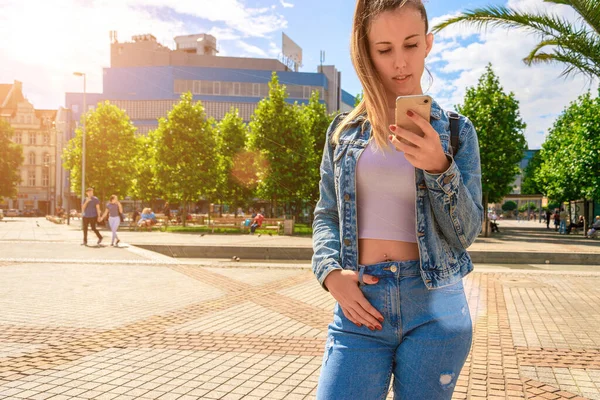 Životní styl. Šťastná mladá dívka s telefonem úsměv, psaní SMS a brát selfie v letním slunci městského města. Moderní technologie zubatý smích odpočinek relax chill lifestyle koncept. — Stock fotografie