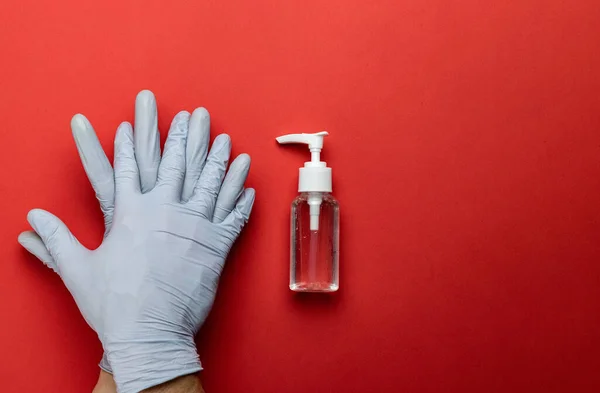 Gel antibacteriano en guantes de laboratorio Usando sobre fondo rojo médico. Limpieza de la higiene de las manos para prevenir brotes de coronavirus. Desinfectante transparente en botella de la bomba, medidas preventivas del Coronavirus — Foto de Stock