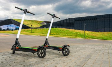 Scooter 'ı tekmele. Şehir yaşam tarzı arka planında elektrikli bisiklet. Modern ve ekolojik ulaşım kavramı.