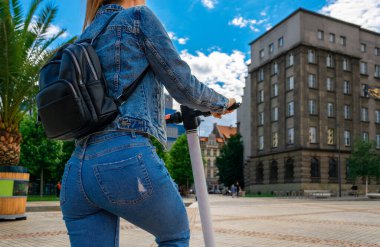 Scooter kızı. İş kadınlarının kullandığı elektrikli şehir bisikletini tekmele. Modern ve ekolojik ulaşım kavramı.