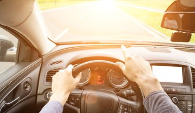 Gün batımında arabanın içinde mutlu bir sürücü. Genç adam yaz güneşli bir günde yolculukta iyi eğlenceler. Tatil konsepti