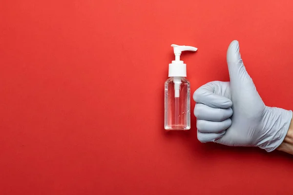 Medical background red. Medical antibacterial sanitizer gel and lab gloves on Virus protection equipment background. Clear sanitizer in pump bottle. Novel Coronavirus 2019-nCoV.