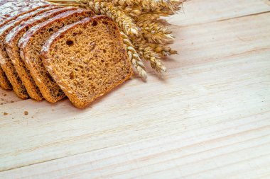 Dilimlenmiş Multigrain. Çavdar ekmeği ve ekmek kırıntılarıyla. Buğday tohumu kulaklı taze bir somun ekmek ya da doğal ahşap arka planda çivili bitki. Biyolojik malzemeler, çok sağlıklı.