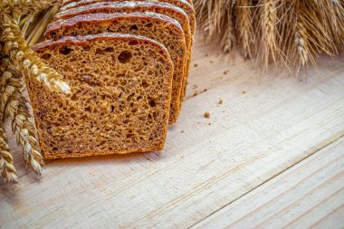 Lezzetli ekmek. Buğday tohumu kulaklı bir somun taze ekmek ya da ahşap desenli bir bitki. Çavdar ekmeği ve ekmek kırıntılarıyla. Ev yapımı pişirme.