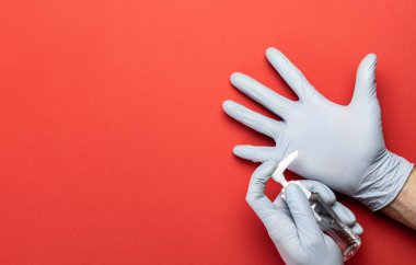Tıbbi ekipman geçmişi. Kırmızıda laboratuvar eldivenlerinde tıbbi alkol dezenfektanı var. Coronavirus hastalığı. Pompa şişesinde dezenfektan var. Koronavirüse karşı koruyucu önlemler.