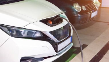 Çevre dostu araba. Melez araç, geleceğin yeşil teknolojisi. Elektrikli araba şarj bataryası eko enerji istasyonunda. Ulaşım ekolojisinin temiz enerji geleceği.