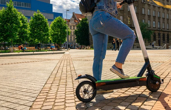 Scooter 'ı tekmele. Elektrikli bisiklet bir kızdan geliyor. Kentsel yaşam tarzı. Modern ve ekolojik ulaşım kavramı. — Stok fotoğraf