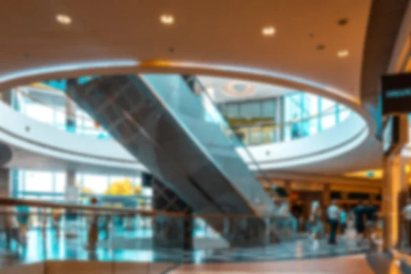 Shopping center building blurred background. People shopping in modern commercial mall center. Interior of retail centre store in soft focus. Image for background use.