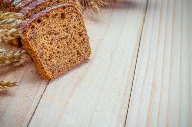 Köy ekmeği. Buğday tohumu kulaklı bir somun taze ekmek ya da ahşap desenli bir bitki. Çavdar ekmeği ve ekmek kırıntılarıyla. Konsept - Evde Yemek Pişirme.