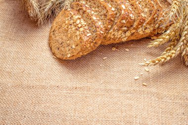 Baget ekmeği. Çavdar ekmeği ve ekmek kırıntılarıyla. Buğday tohumu kulaklı bir somun taze ekmek ya da doğal pamuk arka planında çivili bitki. Konsept - Evde Yemek Pişirme.