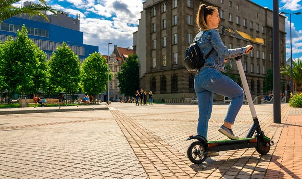 Elektrikli taşıma: Kızdan kullanarak elektrikli şehir scooterını tekmele. Kentsel yaşam tarzı. Elektrik kentsel ulaşım kavramı. — Stok fotoğraf
