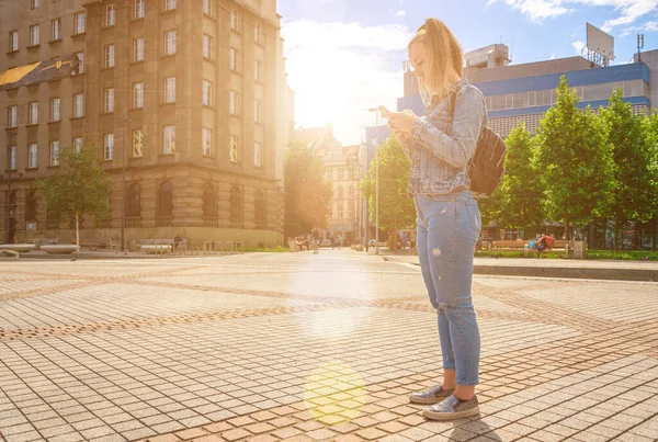 Travel blog. Happy young girl with phone smile, typing texting and taking selfie in summer sunshine urban city. Modern technology toothy laughter rest relax chill lifestyle concept. — Stock Photo, Image