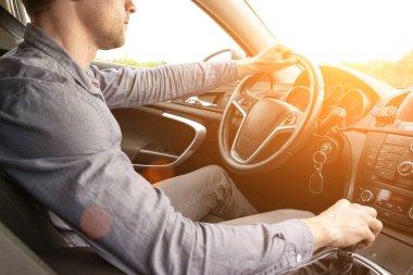 Gün batımında arabanın içinde mutlu bir sürücü. Genç adam yaz güneşli bir günde yolculukta iyi eğlenceler. Tatil konsepti.