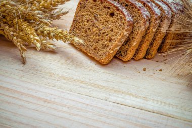 Fırın ürünleri. Çavdar ekmeği ve ekmek kırıntılarıyla. Buğday tohumu kulaklı taze bir somun ekmek ya da doğal ahşap arka planda çivili bitki. Konsept - Evde Yemek Pişirme.