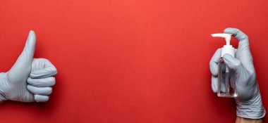Tıbbi eldivenler, antibakteriyel dezenfektan jeli, kırmızı arka planda virüs koruma ekipmanı. Pompa şişesinde dezenfektan var. Corona Virüsü sık sık ellerini yıkayarak salgın hastalıktan korunuyor.
