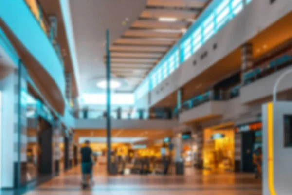 Shopping center blurred background. People shopping in modern commercial mall center. Interior of retail centre store in soft focus. Image for background use.