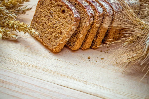 Traditional bread. Fresh loaf of rustic traditional bread with wheat grain ear or spike plant on wooden texture background. Rye bakery with crusty loaves. Design element for bakery product label