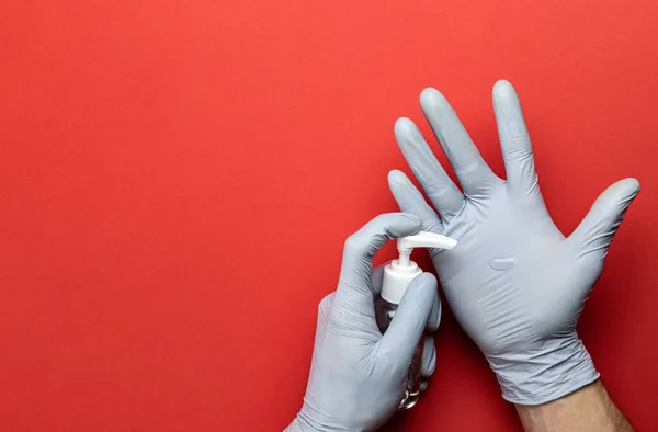 Lavarse las manos aisladas en rojo. Uso de gel desinfectante médico en guantes de laboratorio sobre fondo rojo. Desinfectante transparente en botella de bomba. Limpieza de la higiene de las manos para la prevención de brotes de coronavirus — Foto de Stock