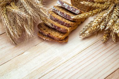 Somun ekmek. Çavdar ekmeği ve ekmek kırıntılarıyla. Buğday tohumu kulaklı taze bir somun ekmek ya da doğal ahşap arka planda çivili bitki. Biyolojik malzemeler, çok sağlıklı tohumlar.