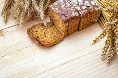Lezzetli ekmek. Buğday tohumu kulaklı bir somun taze ekmek ya da ahşap desenli bir bitki. Çavdar ekmeği ve ekmek kırıntılarıyla. Ev yapımı pişirme.