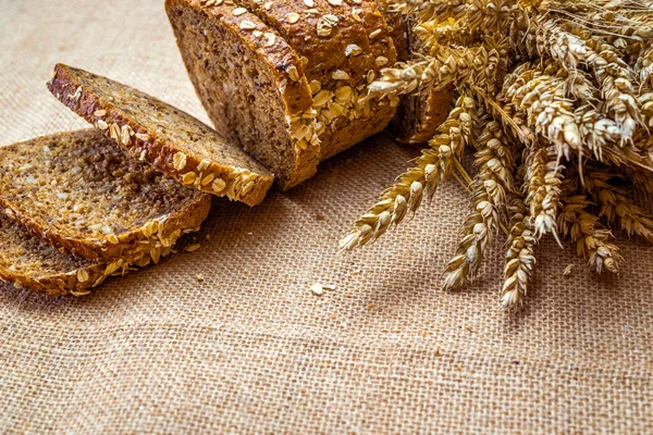 Home baked bread. Rye bakery with crusty loaves and crumbs. Fresh rustic traditional bread with wheat grain ear or spike plant on natural cotton background. Design element for bakery product label