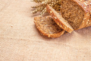 Çavdar ekmeği izole. Kabuklu somun ve ekmek kırıntılarıyla fırın. Buğday tohumu kulaklı bir somun taze ekmek ya da doğal pamuk arka planında çivili bitki. Biyolojik malzemeler, tohumlarla sağlıklı.