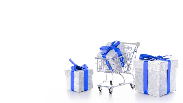 Birthday shopping. Trolley cart for supermarket with christmas or birthday gift box isolated on white background. Sale, discount, shopaholism concept. Consumer society trend