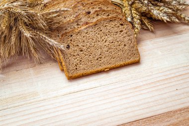 Köy ekmeği. Buğday tohumu kulaklı bir somun taze ekmek ya da ahşap desenli bir bitki. Çavdar ekmeği ve ekmek kırıntılarıyla. Konsept - Evde Yemek Pişirme