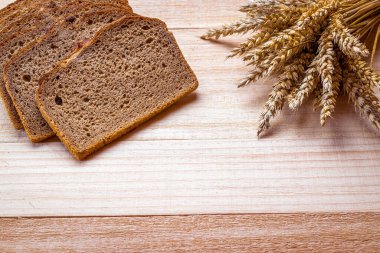 Taze pişmiş ekmek. Buğday tohumu kulaklı bir somun taze ekmek ya da ahşap desenli bir bitki. Çavdar ekmeği ve ekmek kırıntılarıyla. Sağlıklı gıda konsepti