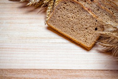 Köy ekmeği. Buğday tohumu kulaklı bir somun taze ekmek ya da ahşap desenli bir bitki. Çavdar ekmeği ve ekmek kırıntılarıyla. Konsept - Evde Yemek Pişirme