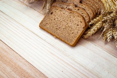 Fırın ürünleri. Çavdar ekmeği ve ekmek kırıntılarıyla. Buğday tohumu kulaklı taze bir somun ekmek ya da doğal ahşap arka planda çivili bitki. Konsept - Evde Yemek Pişirme.