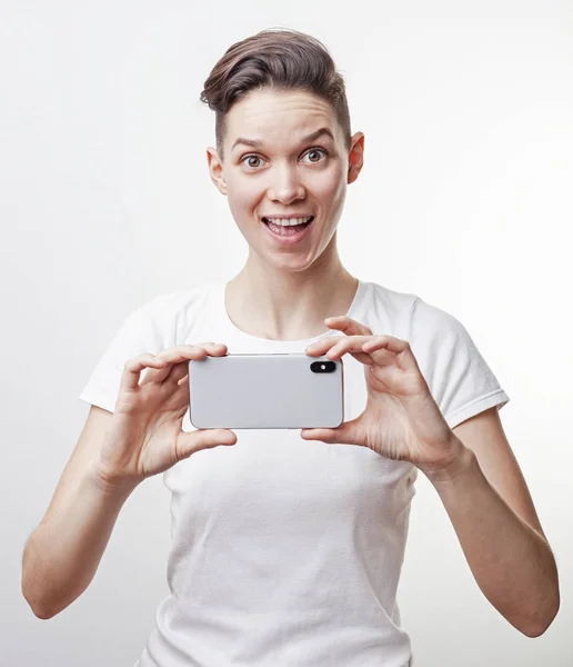Linda menina adolescente asiática sorrir e tirar uma foto usando a câmera frontal em seu smartphone, isolado no fundo branco . — Fotografia de Stock