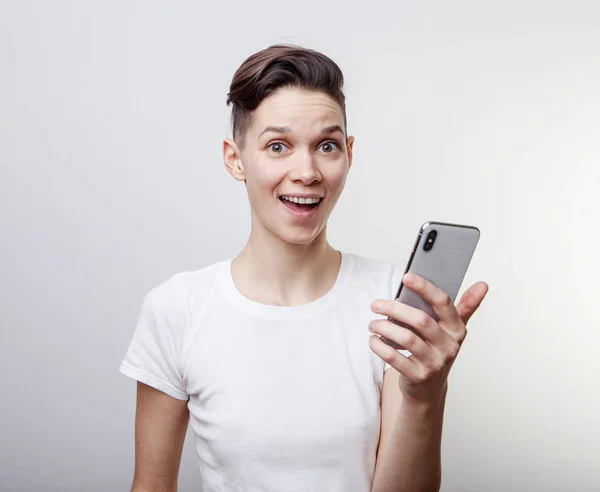 Glücklich lustig Millennial Frau feiert Sieg oder Sieg, Triumph, hält ein Telefon. fröhlich aufgeregtes Mädchen, lachend, Spaß habend, Handy-Apps nutzend. isoliert auf weißem Studiohintergrund. — Stockfoto