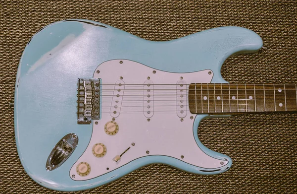 Hafif mavi elektro gitar bir doku arka planda. Yaş yıpranmış gitar