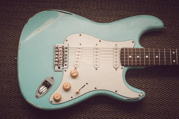 Hafif mavi elektro gitar mor doku arka planda. Yaş yıpranmış gitar
