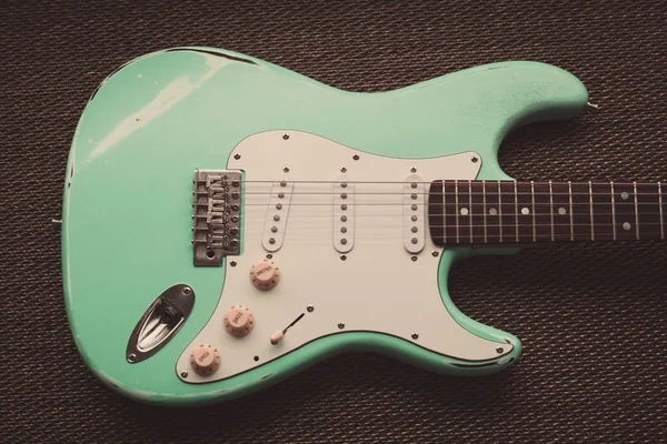 Light green electric guitar in a purple texture background. Age worn guitar