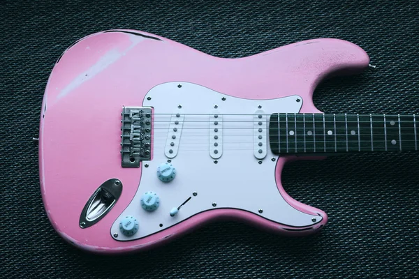 Hafif pembe elektro gitar doku arka planda. Yaş yıpranmış gitar