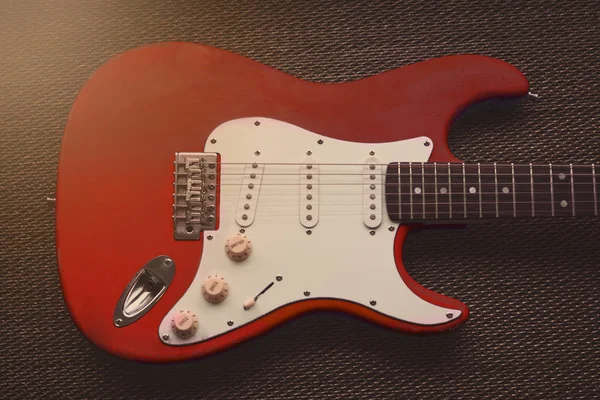 Kırmızı Lal elektro gitar bir desen doku arka planda. Yaş yıpranmış gitar
