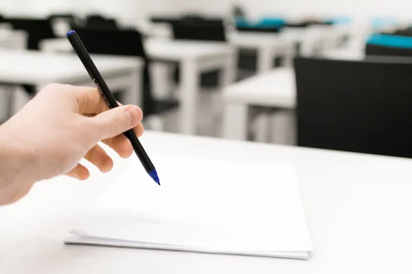 Sınıf boş. Yüksek okul veya üniversite öğrencisi kalem yazma kağıt cevap sayfası üzerinde tutarak. Sınav test odası