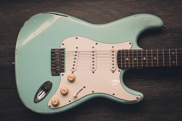 Light blue electric guitar against brown wood background