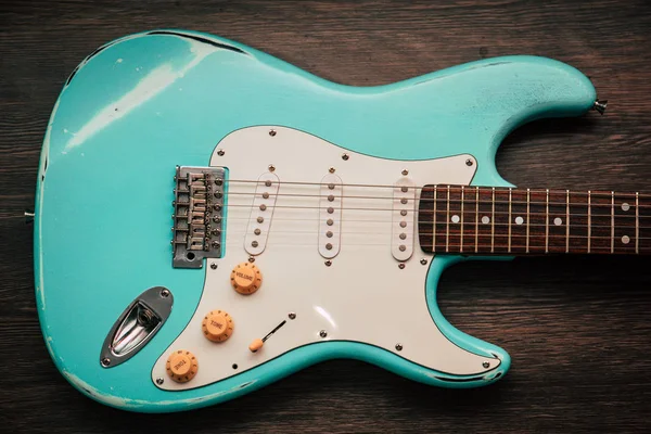 Licht blauwe elektrische gitaar tegen bruin houten achtergrond — Stockfoto