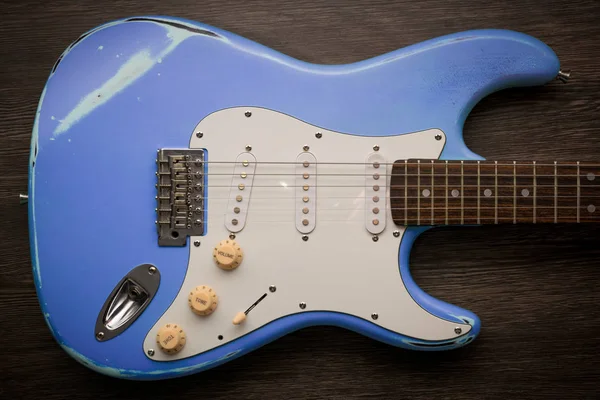 Blue electric guitar against brown wood background. Vintage age worn guitar.